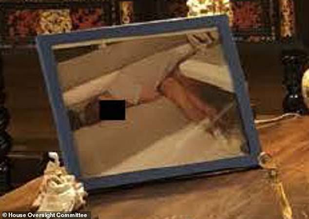 A framed photo on the right corner of the desk facing toward Epstein appears to show a person lying down. A black box has been placed over their face to protect their identity