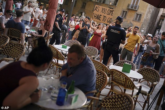 Tourists sit in a restaurant as people protest against overtourism in the Balearic island of Mallorca, Spain, Sunday, June 15, 2025