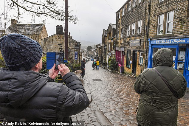 Sian Alison, who owns a boutique shop on Main Street selling handcrafted jewellery and Italian leather handbags, told how the movie was 'making a difference' to local footfall. Pictured: Tourists on the village's Main Street