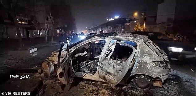 A burnt car lies on the road following unrest sparked by dire economic conditions, in a place given as Tehran, Iran, January 10, 2026