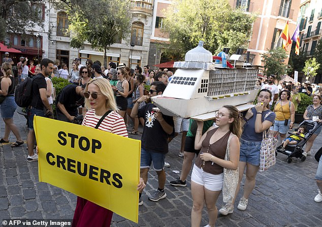 Demonstrators hold a cardboard cruise boat during a protest against mass tourism and housing prices in Palma de Mallorca, on the Balearic island of Mallorca on June 15, 2025