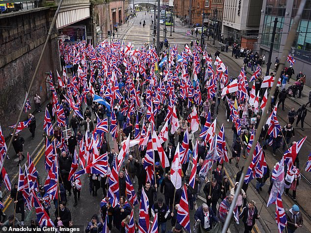 Demonstrators carrying UK flags gather to march for anti-migration protest as they demand mass deportation in Manchester