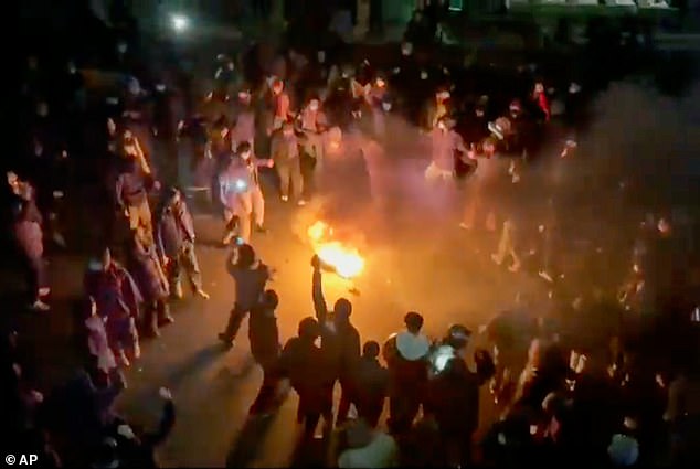 Pictured: Protesters dancing and cheering around a bonfire as they take to the streets to protest against the Islamic Republic