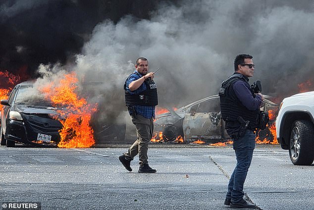 Police officers secure the area where vehicles were set on fire by organized crime members to block a road following a military operation in which a government source said Mexican drug lord Nemesio Oseguera, commonly known as "El Mencho," was killed, in Zapopan, Mexico, February 22, 2026. REUTERS/Gilberto Gallo     TPX IMAGES OF THE DAY