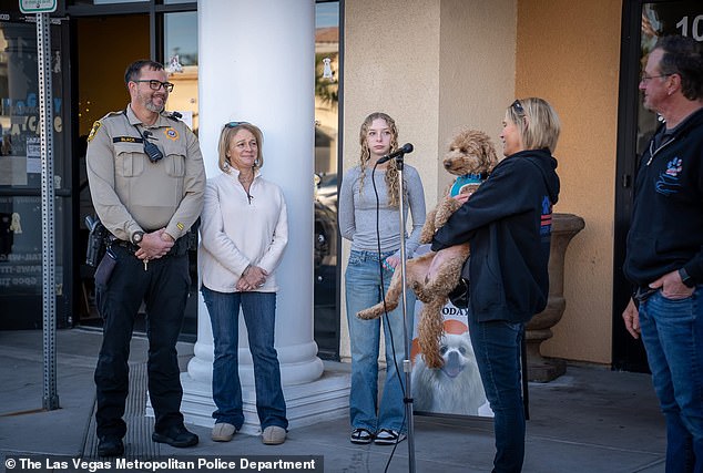 Officer Black and his family smiling widely as they held the two-year-old furball during the adoption finalization process
