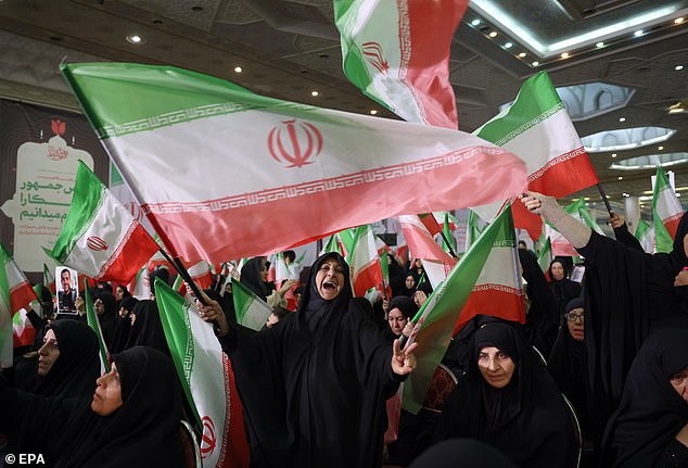 Iranian women wave Iran's national flags during a memorial ceremony for those killed in anti-government protests earlier last month, at the Mosallah mosque in Tehran on February 17