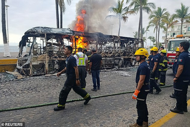 Firefighters work to extinguish flames from buses set on fire by members of organized crime group at a tourist area in Puerto Vallarta, Mexico on Sunday