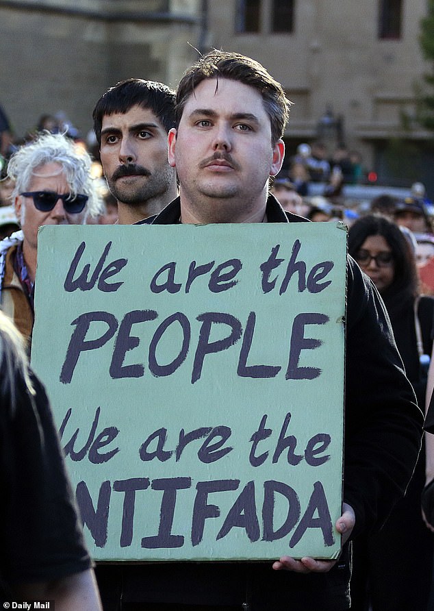 A protester carries a placard carrying a controversial phrase condemned by the Jewish community as a call for violence (It is not suggested anyone pictured was a paid protester)