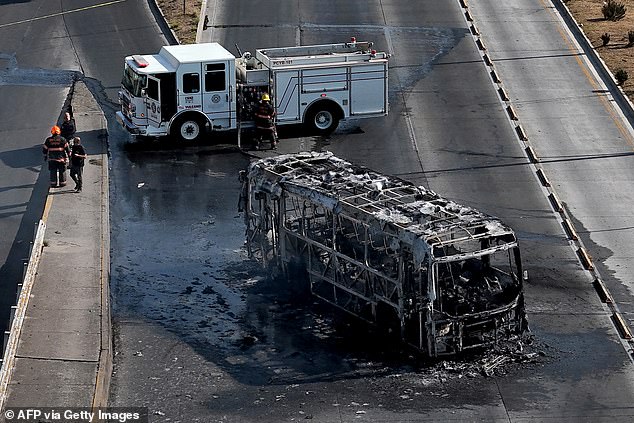 Firefighters extinguish a burning bus set on fire by organized crime groups in response to an operation in Jalisco to arrest a high-priority security target, at one of the main avenues in Zapopan, state of Jalisco, Mexico on Sunday