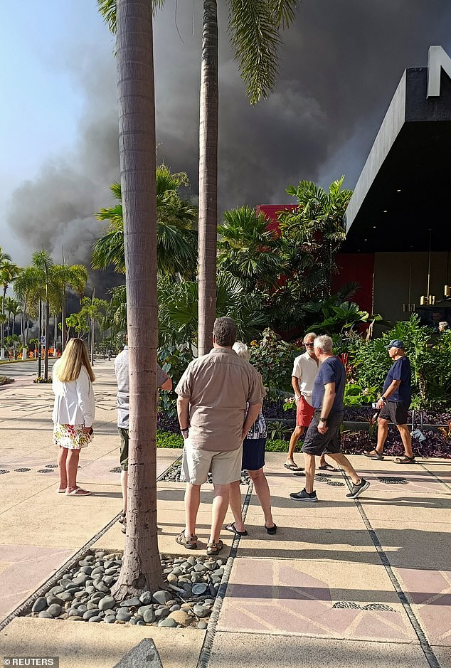 Tourists watch a column of smoke amid ongoing violence in Puerto Vallarta, Mexico, on Sunday