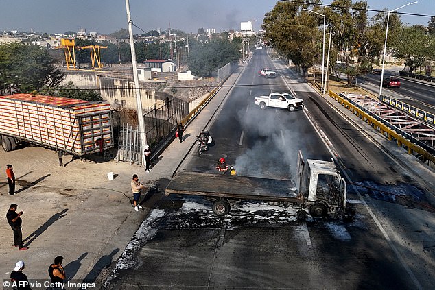 A man extinguishes a burning truck set on fire by organised crime groups