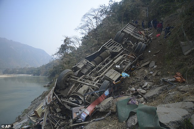 The wreckage of a bus is seen on the bank of the Trishuli River after it drove off a mountain highway near Benighat, west of the capital, Kathmandu, Nepal