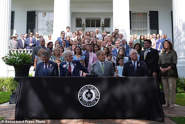 Parents and family of children who died at Camp Mystic join Texas Governor Greg Abbott, second from right, as he signs camp safety bills, last September