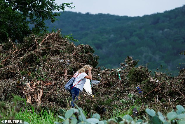 More than 100 people across Central Texas died during the historic July 4 flooding. Pictured, a woman searches the area, following flash flooding last July
