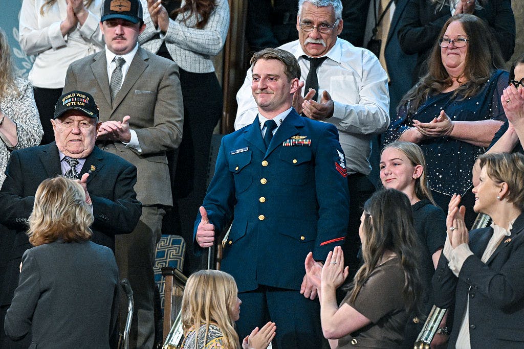 WASHINGTON, DC - FEBRUARY 24: U.S. Coast Guard Petty Officer Scott Ruskan and Milly Cate, a camper who was rescued by Ruskan during the flooding at Camp Mystic, attend President Donald Trump's State of the Union address during a joint session of Congress at the Capitol on February 24, 2026 in Washington, DC. Trump delivered his address days after the Supreme Court struck down the administration's tariff strategy, and amid a U.S. military buildup in the Persian Gulf threatening Iran.