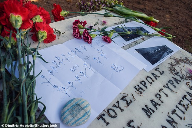Flowers laid at a memorial to the resistance fighters, along with photographs and a drawing of the men