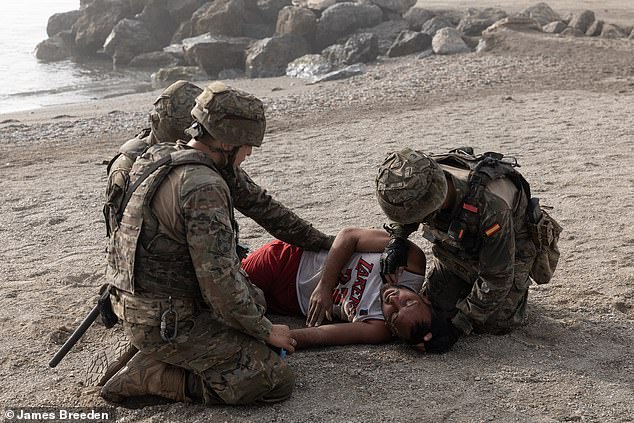 Spanish soldiers come to help the migrant gasping for air on the beach as thousands cross over the border