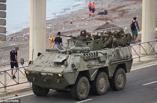 Spanish troops sit in a military vehicle as the authorities escort a big group of migrants to the border to take them out of Spain