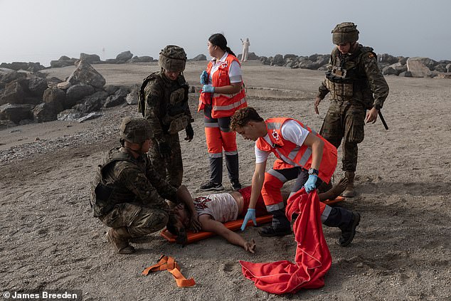 Paramedics put the man on a stretcher and give him first aid as they take him off the beach