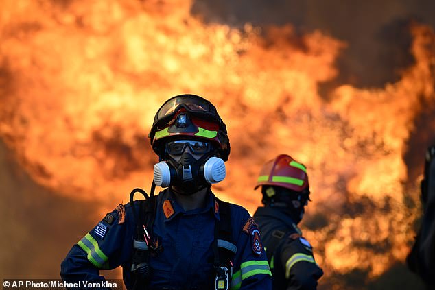 A firefighter stands as flames rise during a wildfire near Porto Germeno, northwest of Athens in Greece