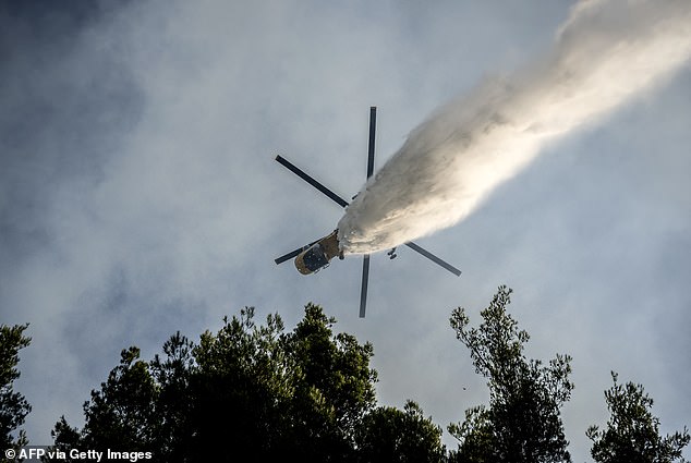A firefighting helicopter drops water over a wildfire in the area of Porto Germeno, just 45 miles of Athens
