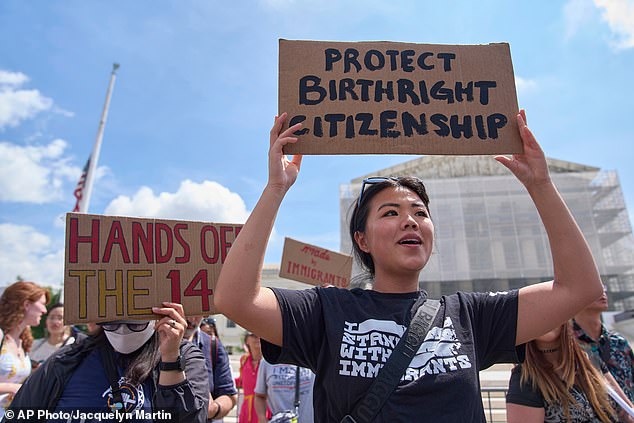 Activists hold signs condemning Trump's move to end birthright citizenship outside of the US Supreme Court in May