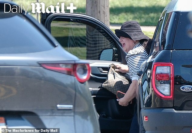 She is seen here laughing after exiting her red, white and black themed Ford earlier this week
