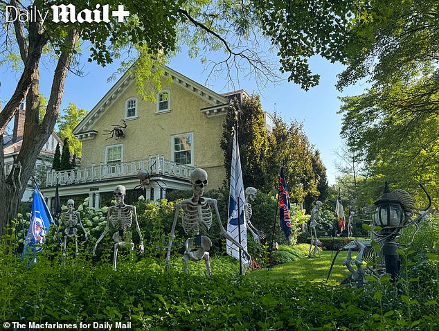 Enormous fake spiders are screwed into the yellow stucco of the home - with more skeletons wielding the flags of Detroit sports teams seen in its gardens