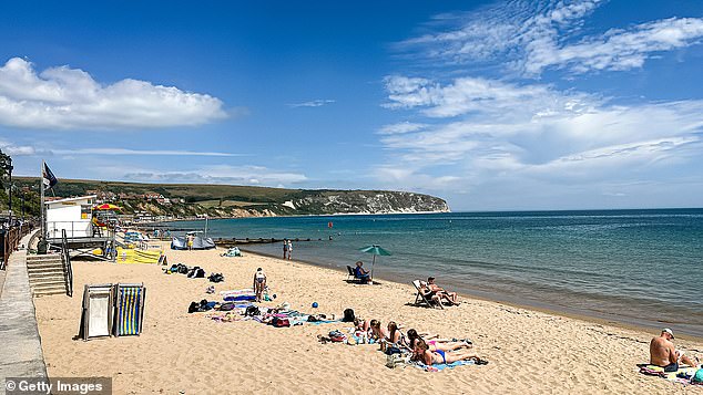 Sunbathers soaked in the rays on a beach in Swanage in Dorset