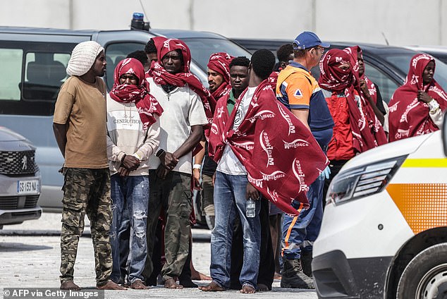 Migrants disembark from a French rescue ship following their rescue at sea after their boat caught fire