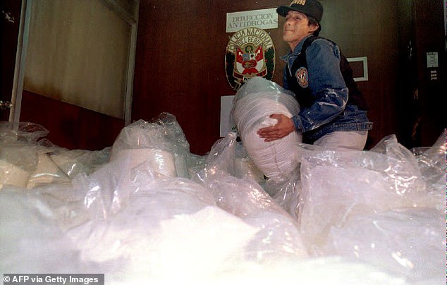 An anti-narcotics policeman lifts a bag of cocaine captured during an anti-drug operation in connection with the Cali drug cartel in Lima, Peru on August 27, 1993