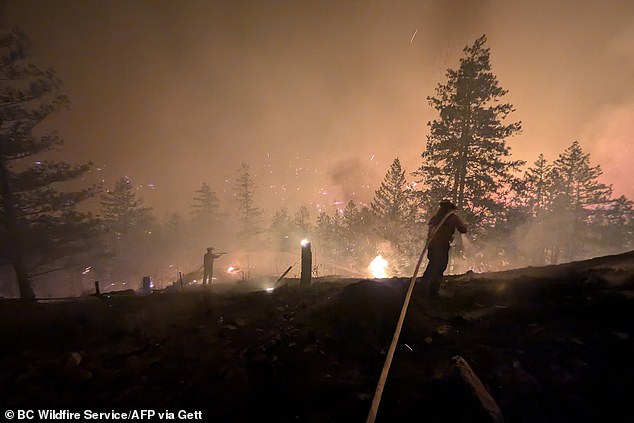 Firefighters can be seen battling the fire on Friday near Summerland, which is about 250 miles east of Vancouver