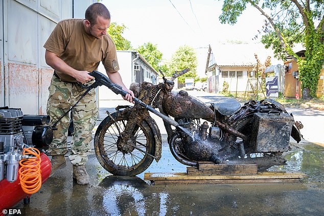 Head of the collection of mechanised military equipment of the Institute and Museum of Military History Jozsef Bakondi cleans a Second World War German military motorcycle DKW NZ 350-1 in Budapest, Hungary, August 5, 2026