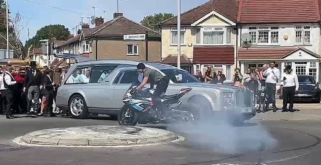 A motorcylist drives past the hearse in Hayes. Traffic was brought to a standstill due to the procession