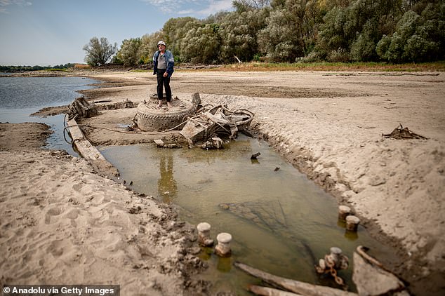 People gather along the exposed riverbed of the Danube, after exceptionally low water levels revealed the remains of an old Second World War-era ship from the riverbed in Baja, Hungary on August 8, 2026