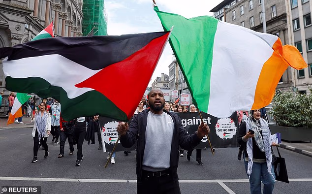 A man holds Irish and Palestinian flags at a protest for governments to stop arming Israel