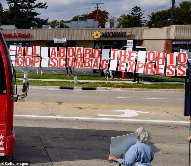 Protesters line an Ohio street with a giant banner declaring demonstrating their opposition to Republicans during the party's statewide campaign bus tour