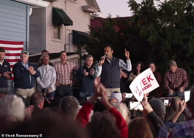 Ramaswamy gestures to cheering supporters at the intimate backyard gathering, where GOP campaign signs filled the crowd while neighbors just across the fence displayed messages supporting his Democratic opponent