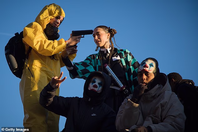 Pictured: One protester holds a prop gun while joining three other protesters in Halloween costumes in Paris