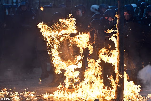 Horrific moment French police officer is engulfed in flames after being struck by Molotov cocktail as violent riots sweep across country