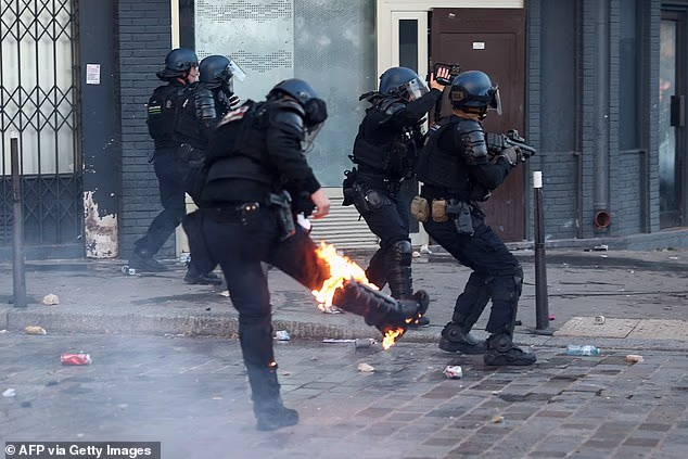 A protester wearing a costume stands next to a burning fire during a demonstration organised by labour unions as part of nationwide protests in Paris
